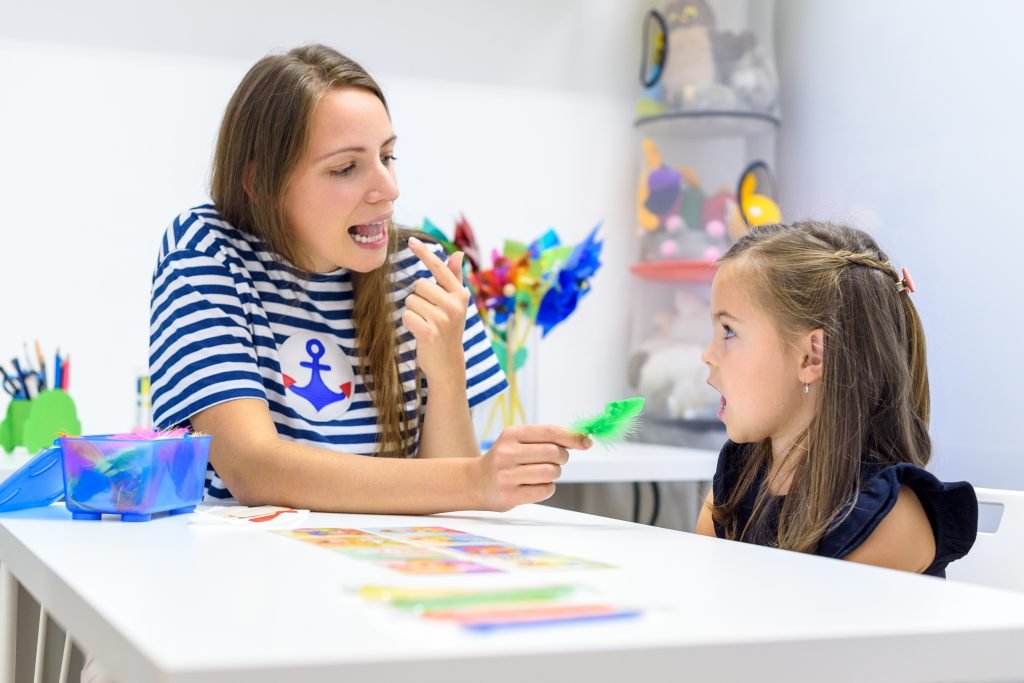 Female speech therapist helping a preschooler practice correct pronunciation