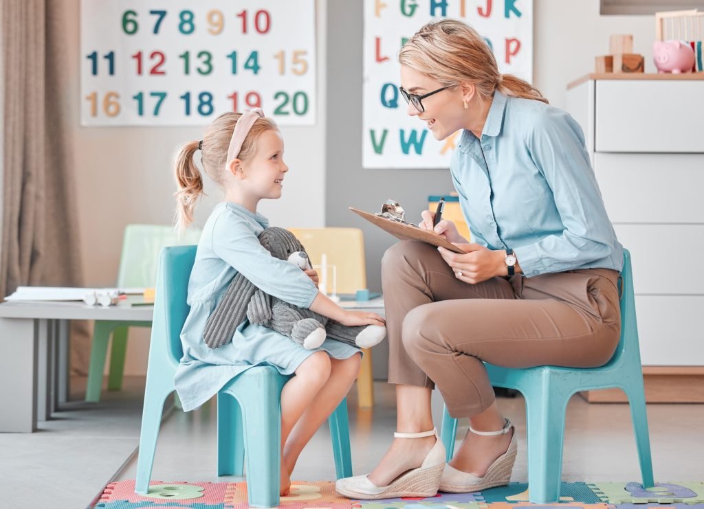 School counselor talking and taking notes with a smiling young girl during a one-on-one counseling session