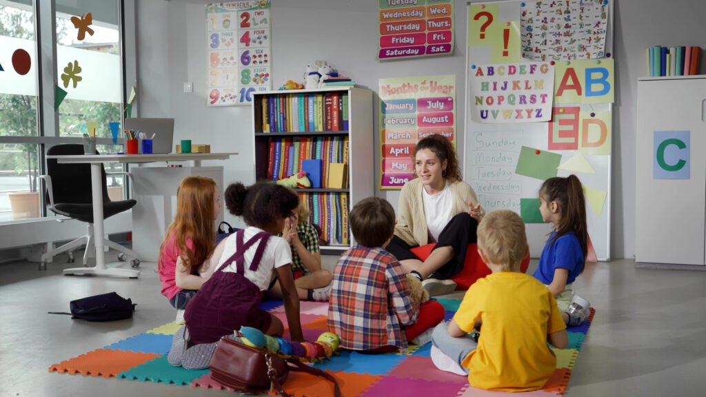 Teacher sitting on the classroom floor with a small group of preschool children during a lesson